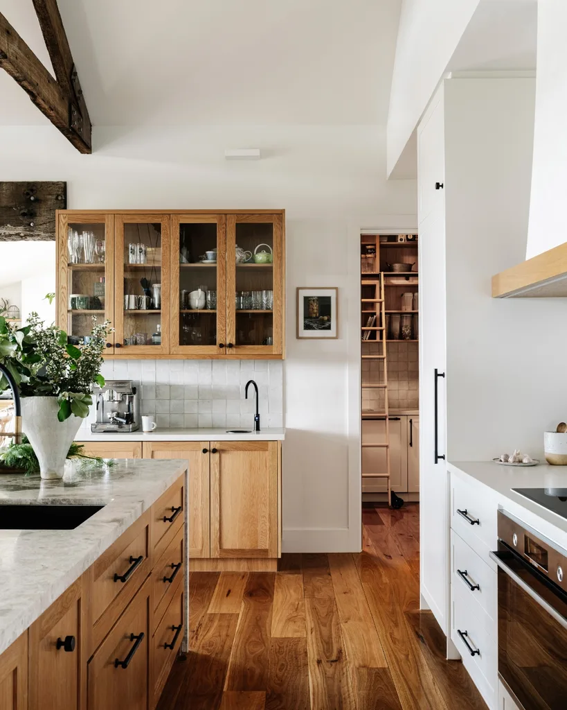 Side view of country style kitchen with timber cabinets and wooden floors.