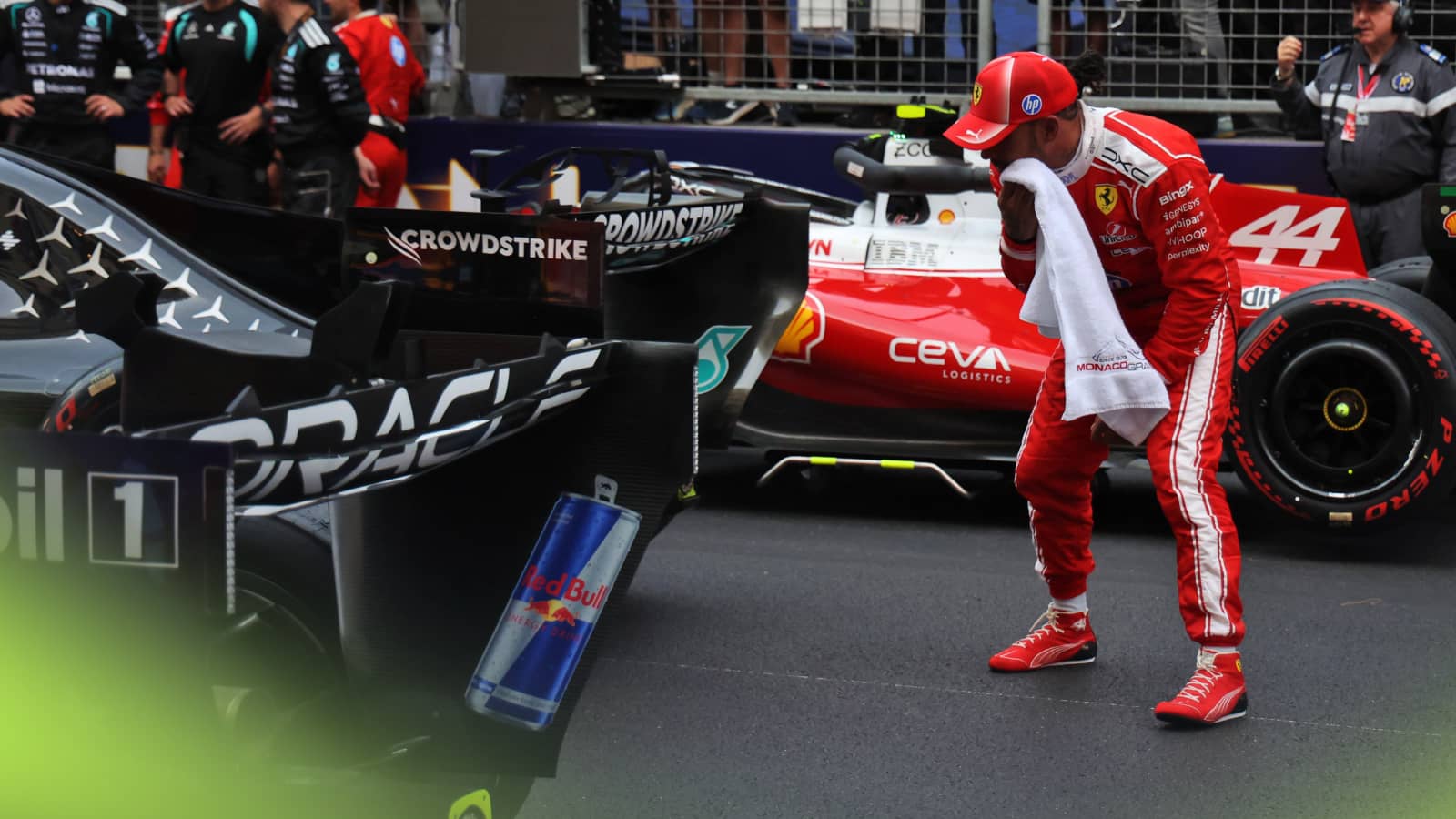Lewis Hamilton crouching behind the rear wing of Kimi Antonelli's Mercedes with a towel pressed to his face