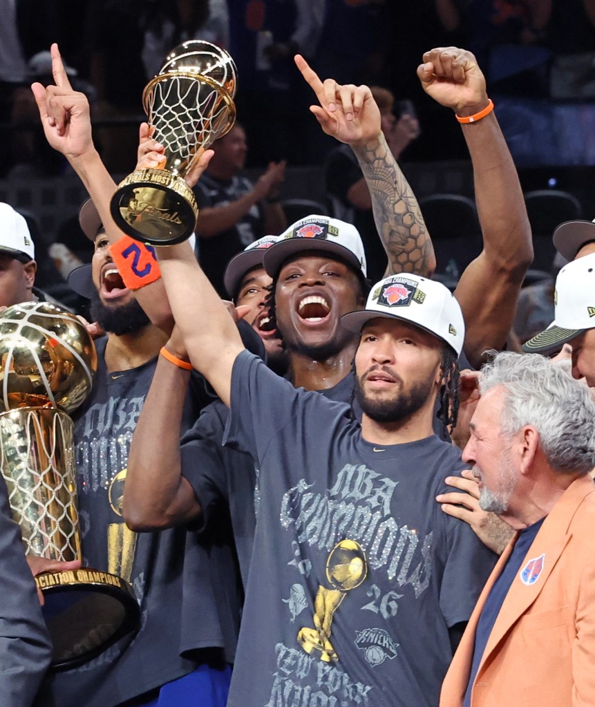 New York Knicks guard Jalen Brunson holding the NBA Finals Most Valuable Player trophy, with forward Og Anunoby behind him, celebrating their championship win.