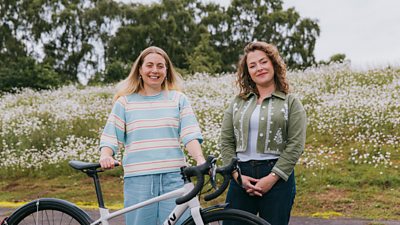 Hannah and Katherine Priddy as Hannah holds a bike smiling at camera
