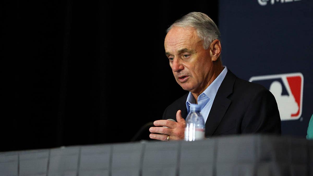 Major League Baseball Commissioner Robert D. Manfred Jr. speaking at a podium indoors.