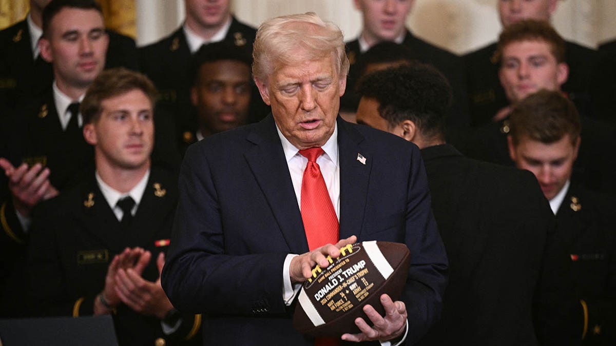President Donald Trump holding a football in the East Room of the White House.