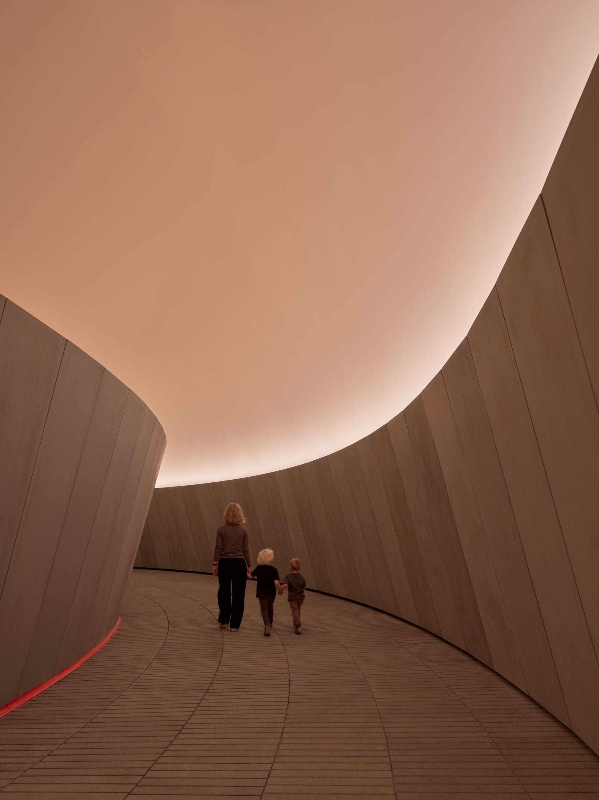 a large-scale light exhibition by James Turrell with people walking down a corridor
