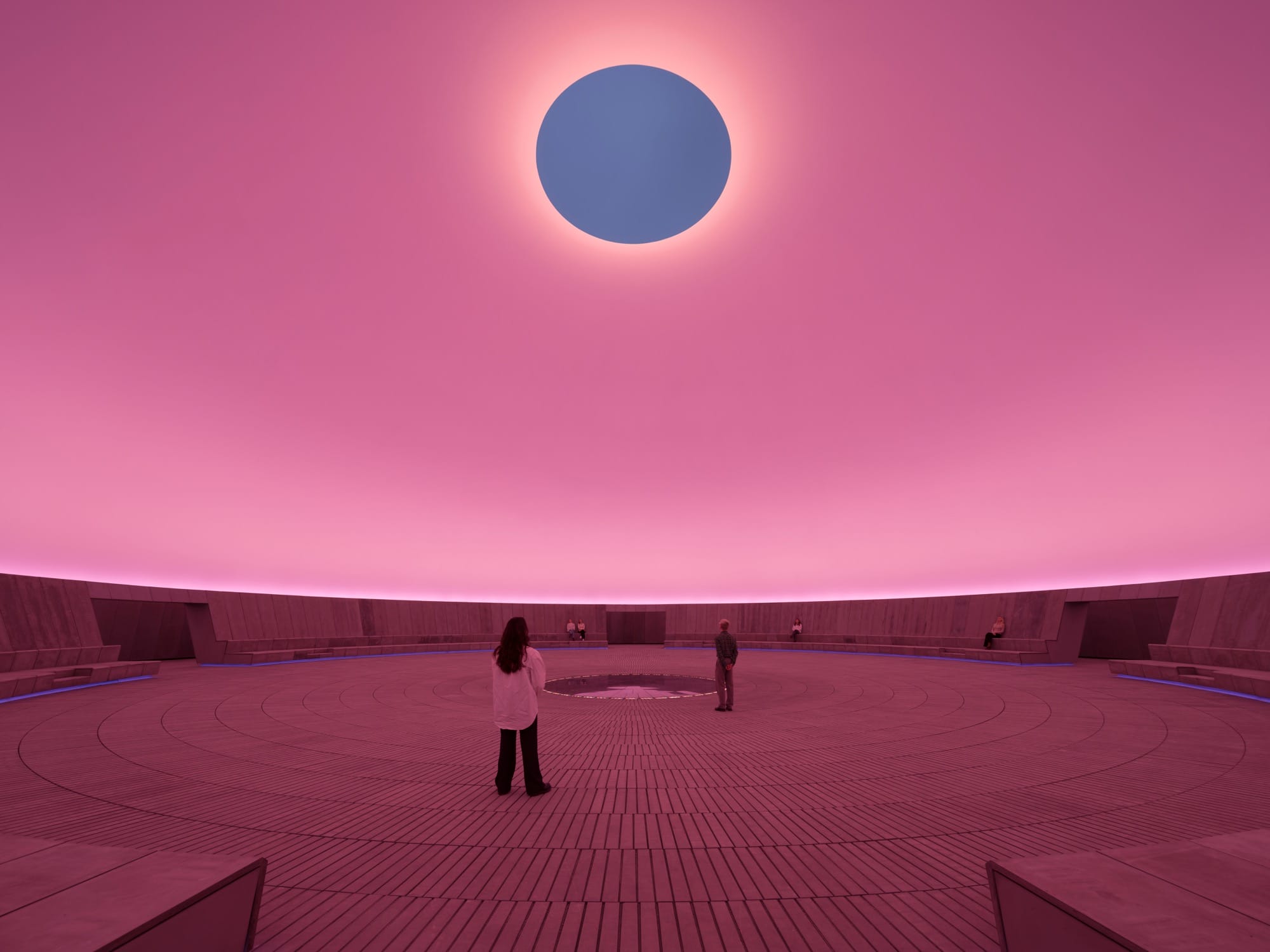 a large-scale light exhibition by James Turrell featuring a gray hole in a pink dome