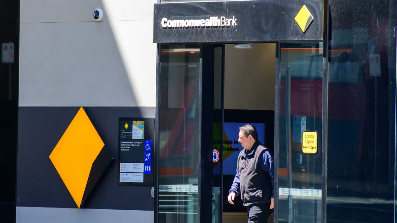 A man walking out of a Commonwealth Bank branch.