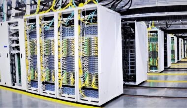 Rows of AI data processing computers stand inside a large warehouse.