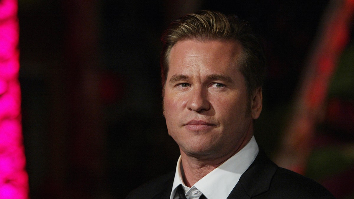 Val Kilmer walking the red carpet wearing a suit and tie