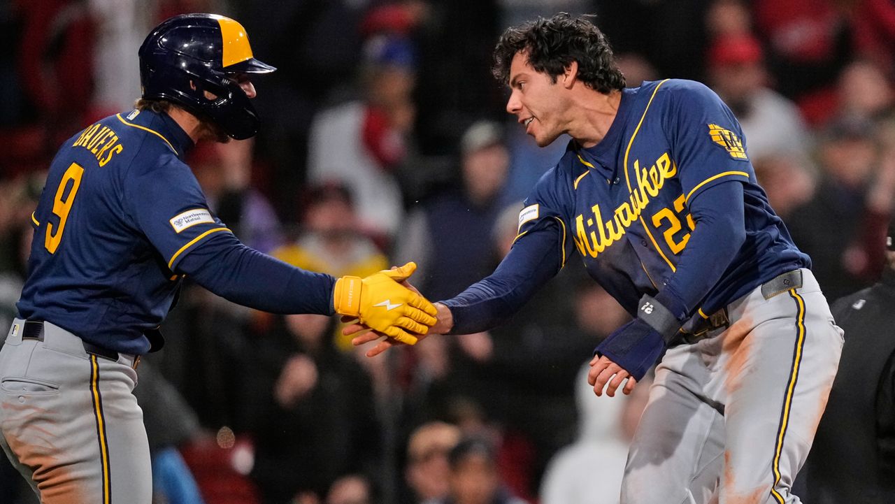 Milwaukee Brewers' Christian Yelich, right, is congratulated by Jake Bauers (9) after scoring on a single by Garrett Mitchell during the eighth inning of a baseball game against the Boston Red Sox at Fenway Park, Monday, April 6, 2026, in Boston. (AP Photo/Charles Krupa)