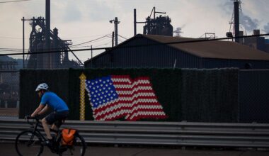 Man cycles past US flag