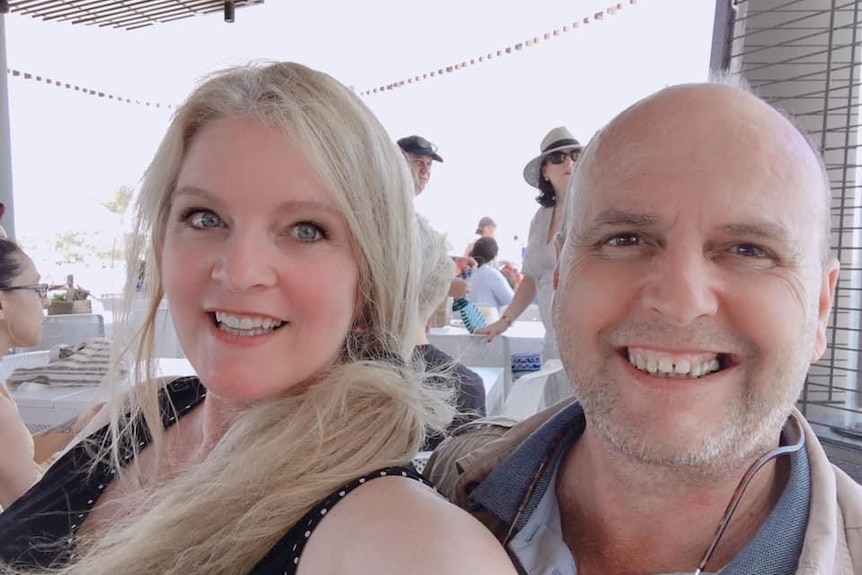 A man and woman take a selfie in a restaurant. They are both smiling at the camera.