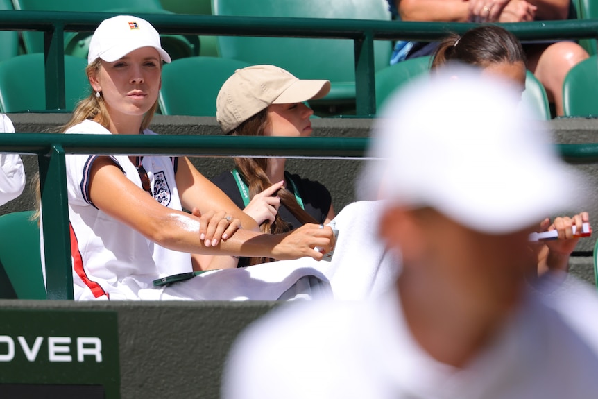 Katie Boulter watches Alex de Minaur, blurry in the foreground, at Wimbledon.