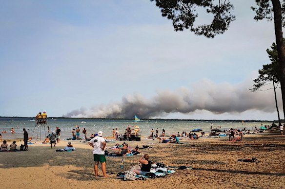 People on the beach in Biscarrosse, southwestern France as a cloud of smoke rises from a fire raging in the northern part of the Arcachon Basin.