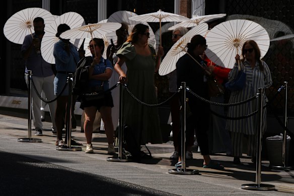 People with parasols queuing outside a shop in London on June 26.