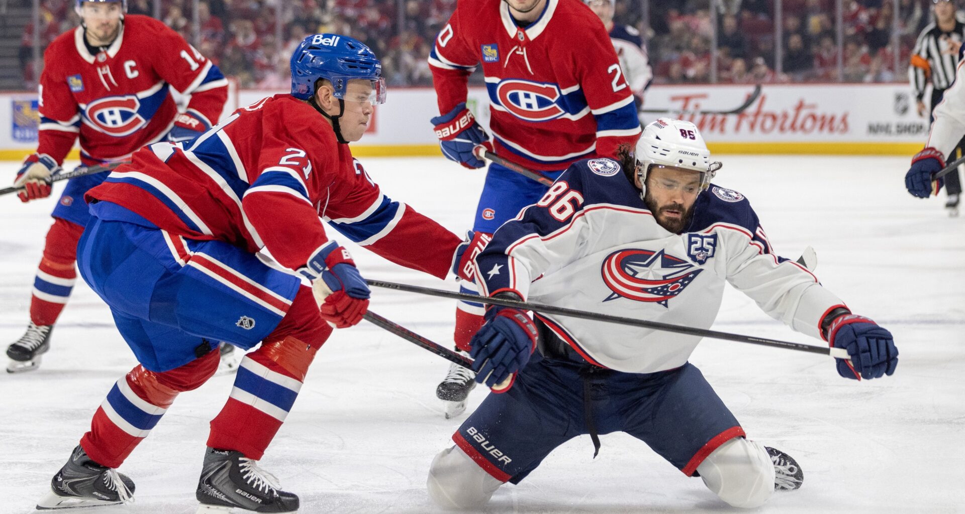 Canadiens defenceman Kaiden Guhle knocks down Columbus Blue Jackets forward Kirill Marchenko as Nick Suzuki, left, and Juraj Slafkovsky trail the play in Montreal on March 26.