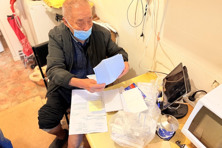 A man in a surgical mask reading papers.