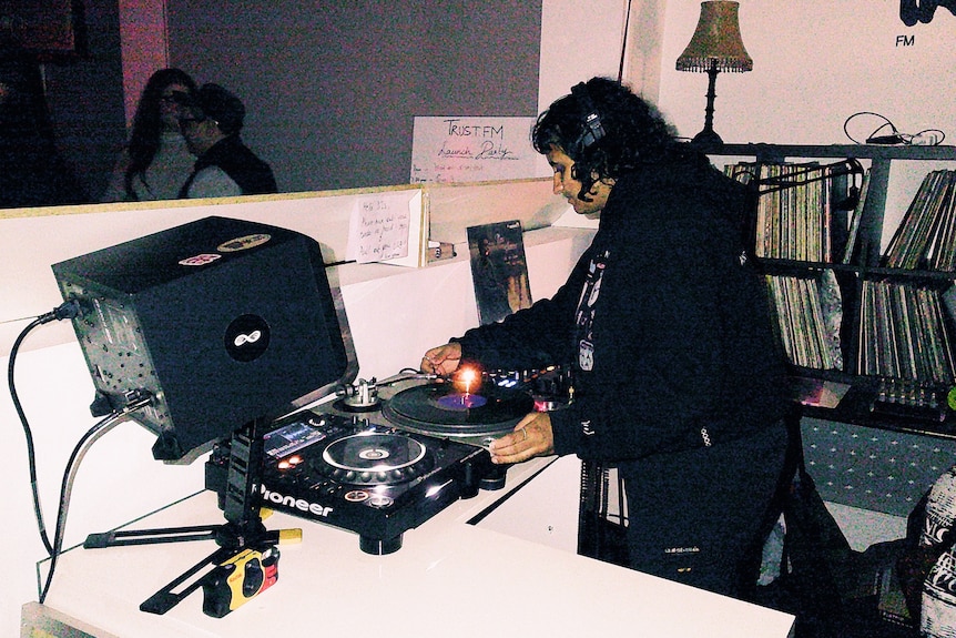 A dj wearing head phones inside a radio studio.