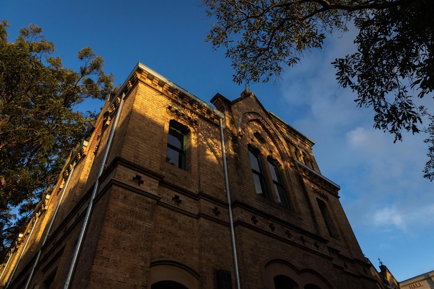 A very large multi-story building made of sandstone blocks on a sunny day.