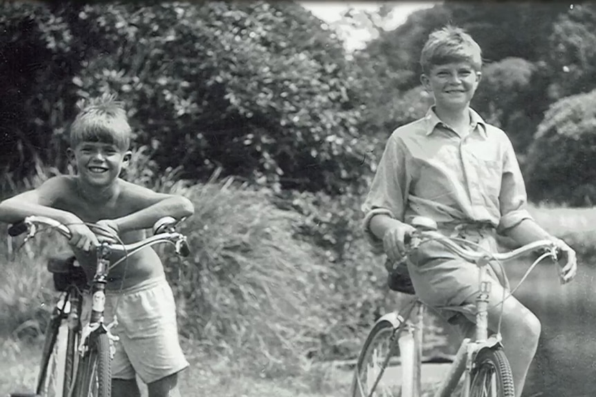 Black and white image two boys on bikes, smiling 