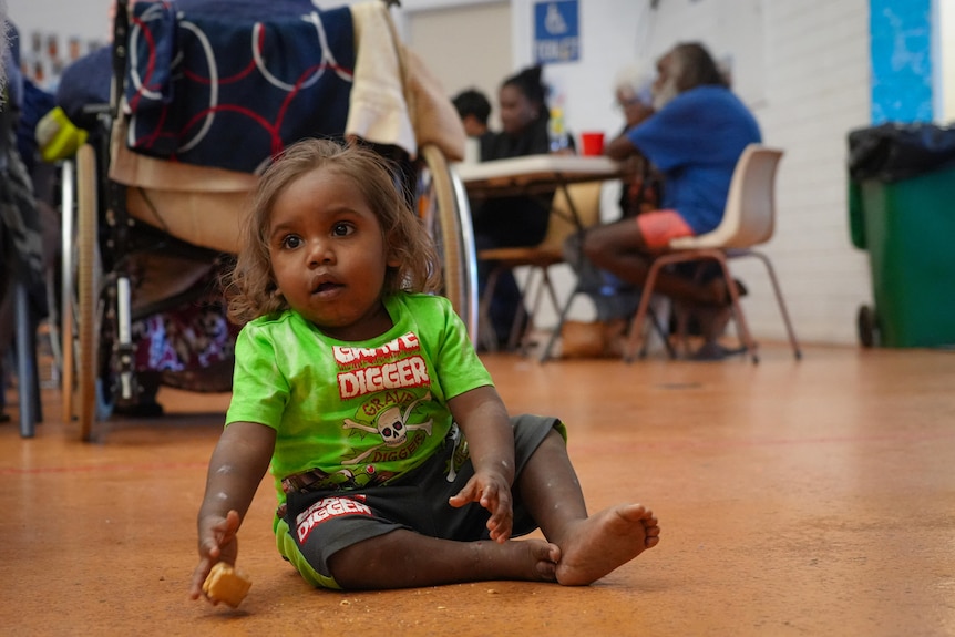 A child plays on the floor during the community meeting.