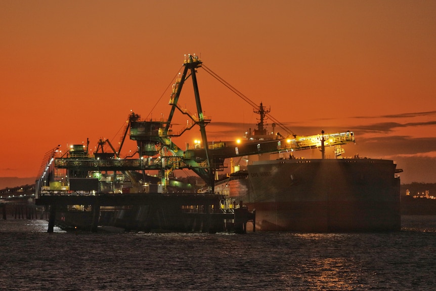 A coal load loads coal onto a large ship