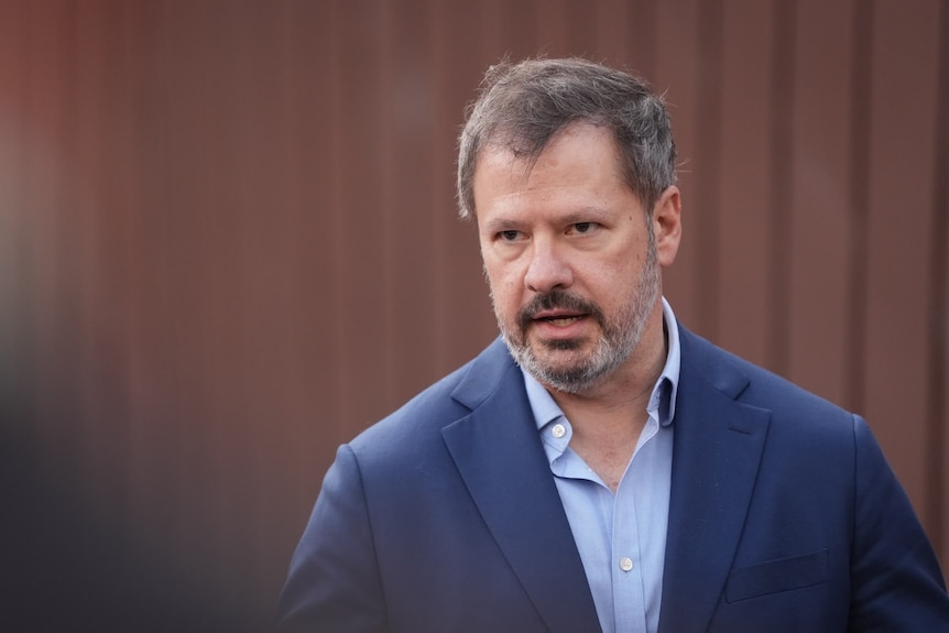 A man in a navy suit and lighter blue shirt