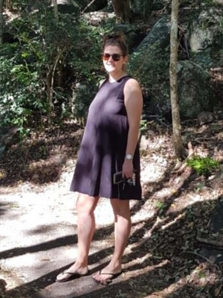 A photo of a woman standing in bushland.
