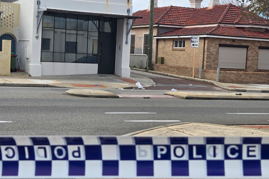Police tape in the foreground of the photo with houses in the background