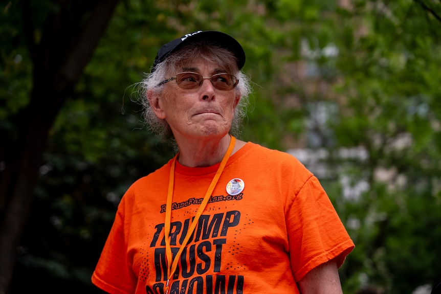 Cindy Luiz wears an orange t-shirt that says 'Trump must go'.