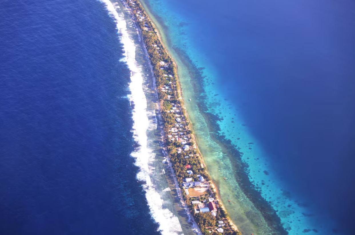Aerial shot of a narrow stip of island surrounded by blue ocean