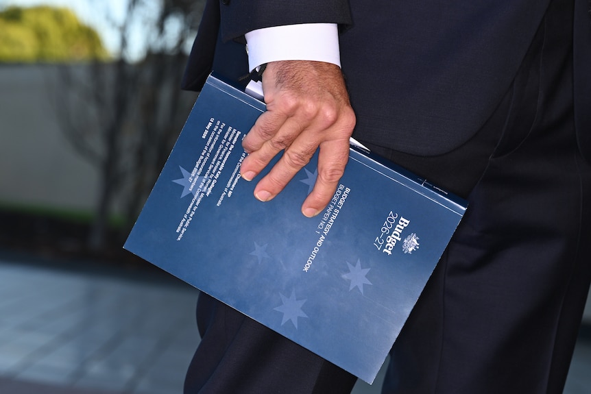 A close up of a hand holding a 2026 federal budget book