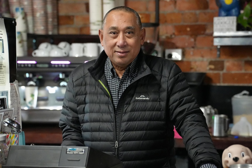 A smiling man behind the counter of a cafe 