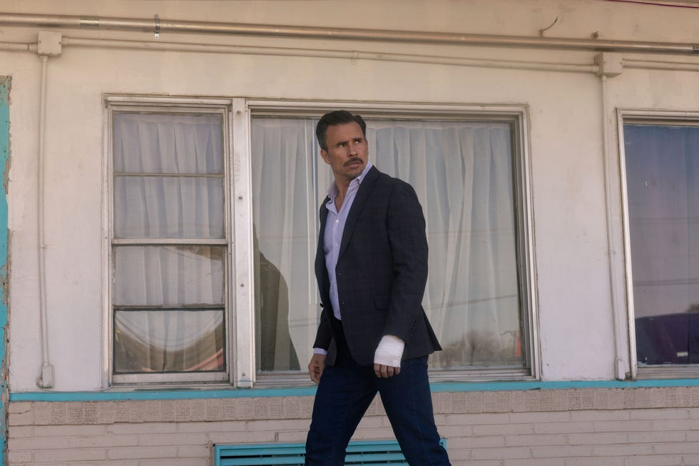 dutton ranch juan pablo raba person in a suit looking to the side, bandaged hand, standing outside.