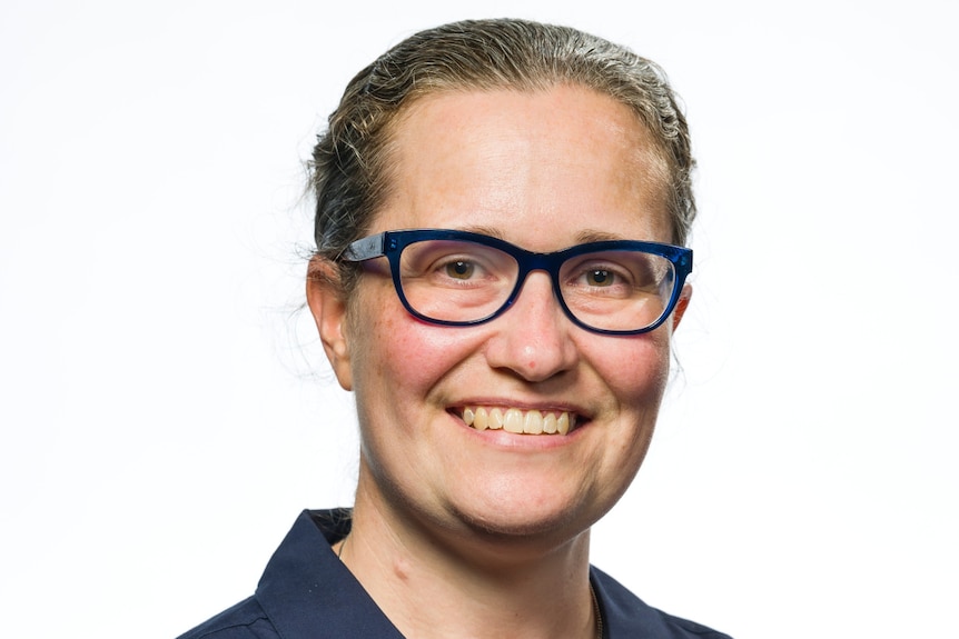 a woman wearing a Queensland Museum branded shirt smiles