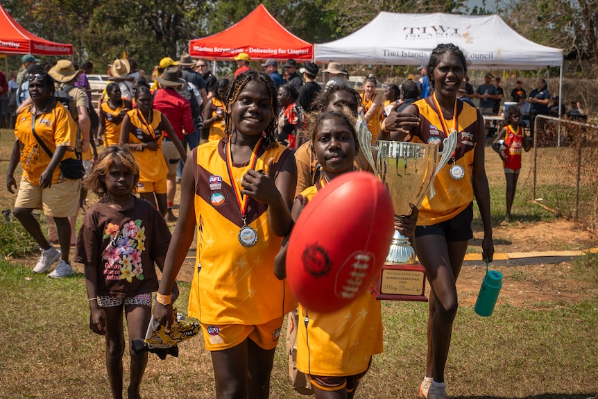 Young women playing with an AFL ball