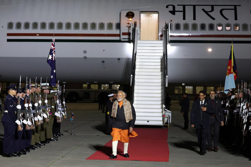 A man walks away from an airplane on a red carpet