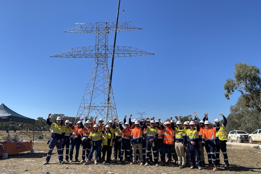 Workers in front of a large powerline.