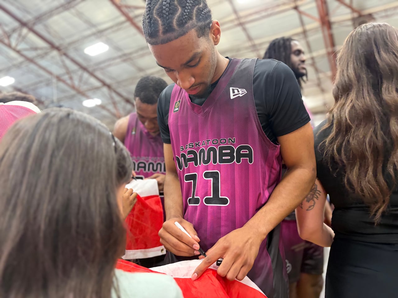 A basketball player signs a Canadian flag for a young kid after the game.