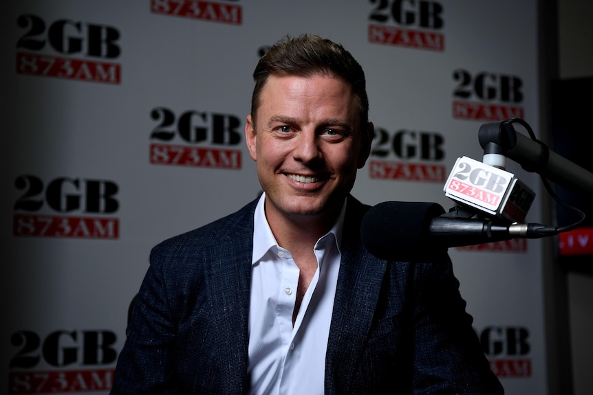 Smiling man behind a microphone, 2GB signage all around
