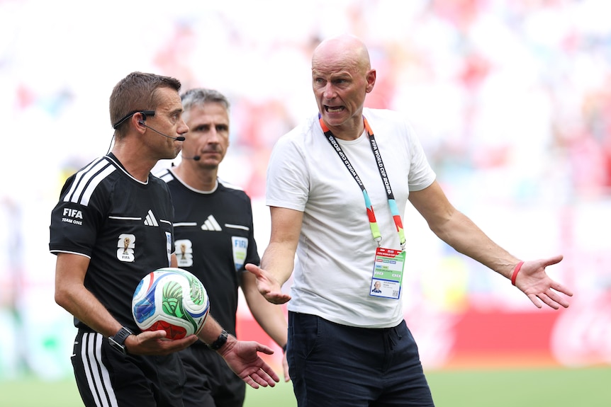 Norway coach Stale Solbokken argues with two referees.