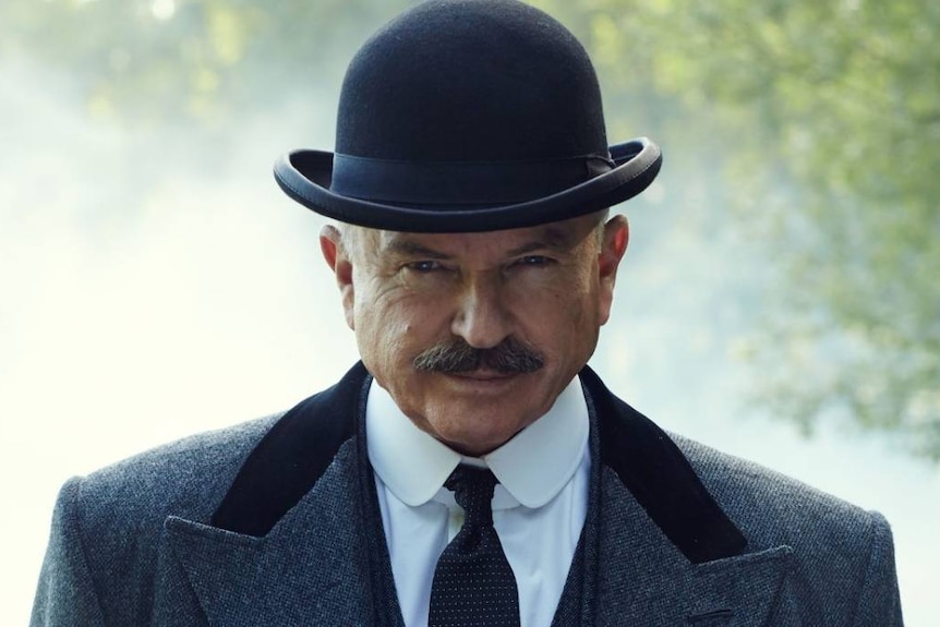 Sam Neill in a bowler hat, looking angry