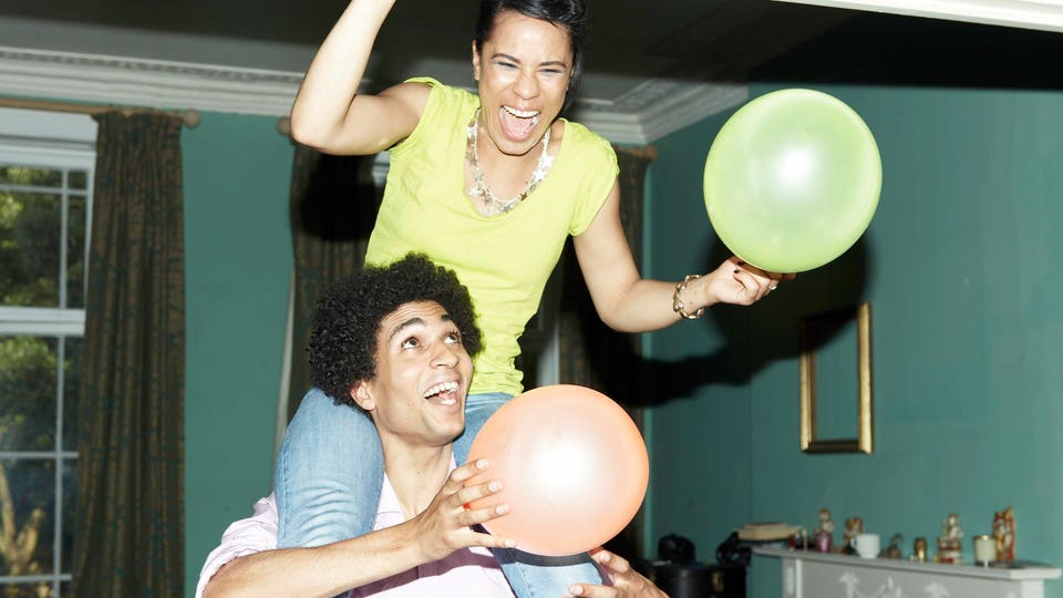 Man carrying woman on shoulders putting up balloon