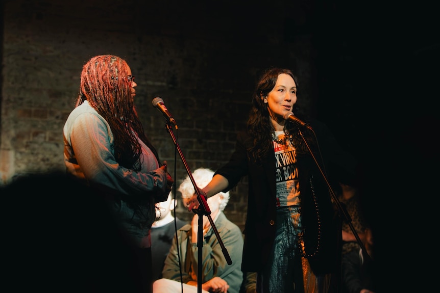 An image of two women standing at microphone stands.