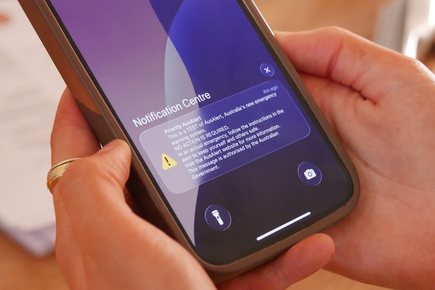A phone notification with the words 'Priority AusAlert'.