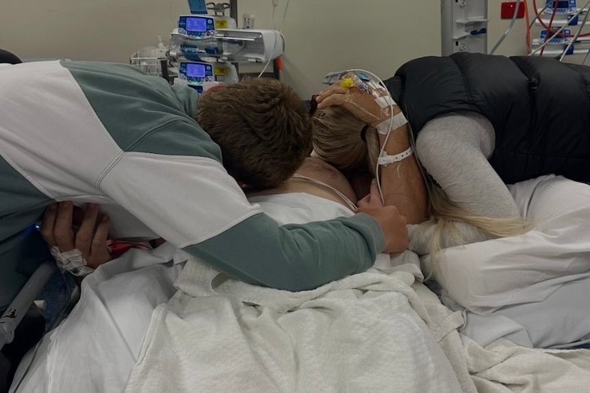 Adelaide Crows legend Tony Modra embraces loved ones in hospital.