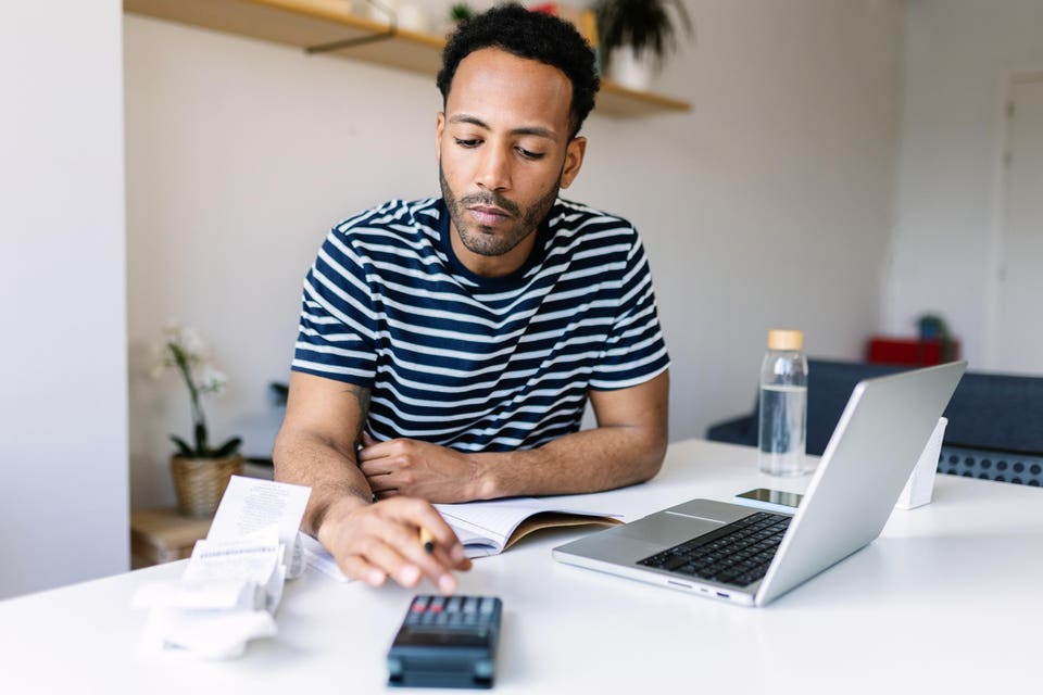 Man with a calculator learning what a k-shaped economy is and how it impacts his finances.