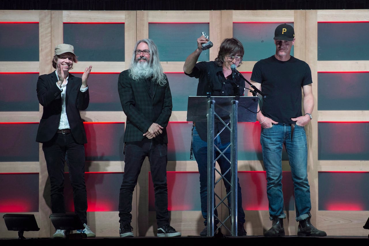 Four members of the band Sloan are shown on stage receiving an industry award.