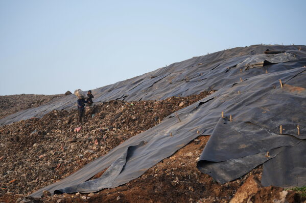 Waste pickers walk near a tarped section at the Bantargebang landfill on the outskirts of Jakarta, Indonesia, Monday, July 6, 2026. (AP Photo/Tatan Syuflana)