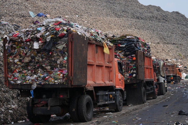 Garbage trucks line up before unloading waste at the Bantargebang landfill on the outskirts of Jakarta, Indonesia, Monday, July 6, 2026. (AP Photo/Tatan Syuflana)