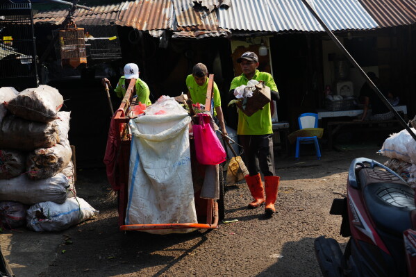 Sanitation workers collect trash at a traditional market in Jakarta, Indonesia, Friday, July 17, 2026. (AP Photo/Tatan Syuflana)