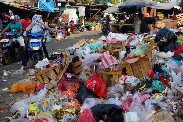 A woman throws a bag of trash onto an open garbage dump in Jakarta, Indonesia, Friday, July 17, 2026. (AP Photo/Tatan Syuflana)